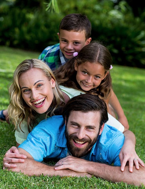 A man, woman and two children playing  in the garden of their new home