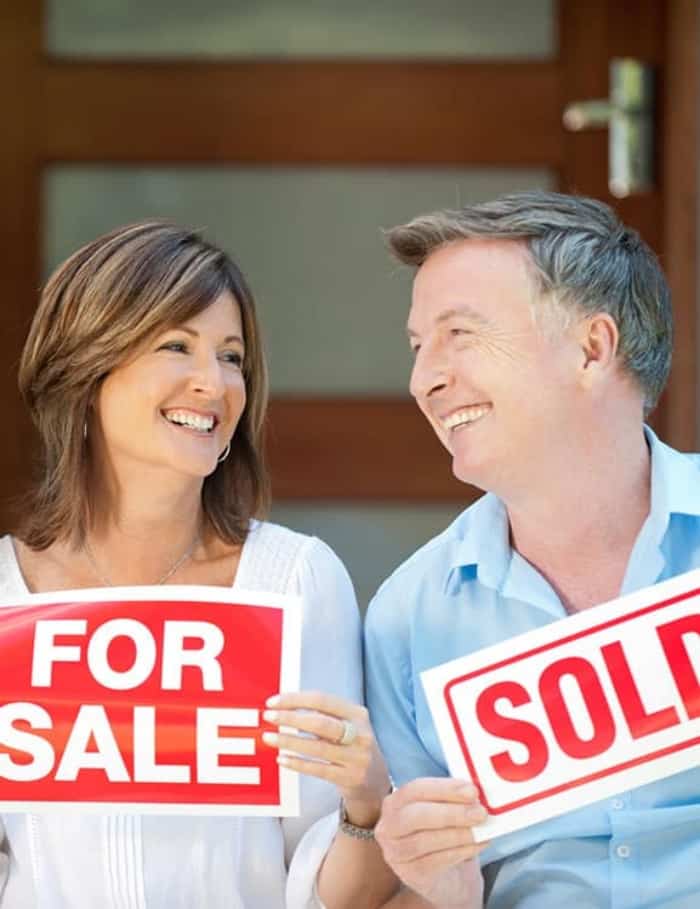 Man and woman holding for sale and sold signs